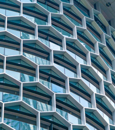 Office buildings. Structure of hexagon windows in futuristic technology network connection concept. Blue glass modern architecture facade design with reflection of sky in urban city, Downtown.